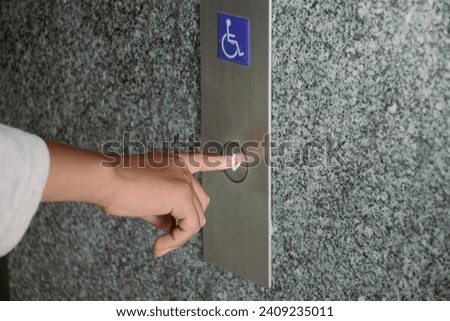 Close-up hand pressing the button for the disabled elevator to go down the building.