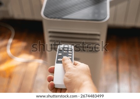 Close-up of a hand pressing the remote control for an air conditioner.