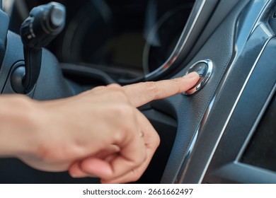 Close-up of hand pressing start button to turn on car engine. Keyless ignition system in modern car