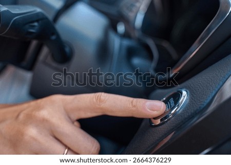 Close-up of hand pressing start button to turn on car engine. Keyless ignition system in modern car