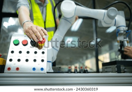 Close-up of hand pressing the stop button on the control panel of an industrial machine.