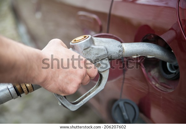 close-up\
of a hand pumping gas in the car with a gas\
pump