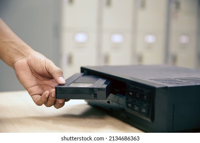 Close-up hand put or insert video cassette tape VHS old retro style on video record playback concept of vintage electric and electronic appliances multimedia player device old fashioned.