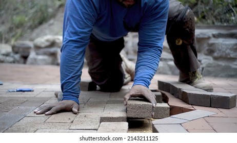 Closeup of hand putting brick paver into place in a hardscaping project. - Shutterstock ID 2143211125