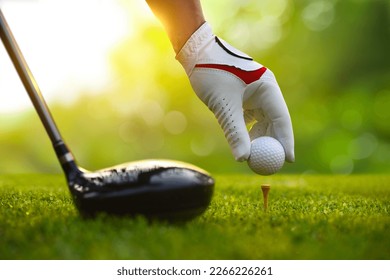 Close-up hand putting golf ball on tee with drivers. - Powered by Shutterstock