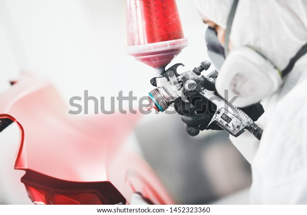 Close-up, hand of repairman painting car body\
elements in the paint\
chamber.