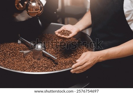 Closeup hand of roaster man control degree of roasting of fresh coffee. Food industry business coffeeshop.