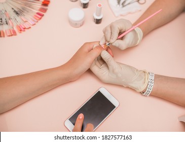 Close-up Of A Hand. In The Salon Of Gel Manicure, The Process Of Drying Gel On Nails, Beauty And Personal Care, Modern Technologies. Work With Gloves. Set Of Nails, Hold The Phone