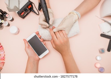 Close-up Of A Hand. In The Salon Of Gel Manicure, The Process Of Drying Gel On Nails, Beauty And Personal Care, Modern Technologies. Work With Gloves. Set Of Nails, Hold The Phone