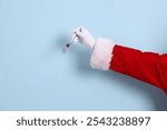 A close-up of a hand of Santa Claus holding up fork, isolated against a blue background. Merry Christmas.