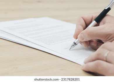 close-up of a hand signing papers - Shutterstock ID 2317828201