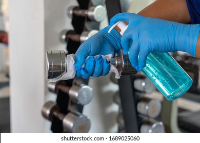 Closeup of hand spraying a blue sanitizer from a bottle for disinfecting dumbbell in gym.Antiseptic,disinfection ,cleanliness and healthcare,Anti bacterial and Corona virus (COVID-19) - Powered by Shutterstock