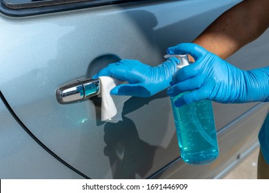 Closeup of hand spraying a blue sanitizer from a bottle for disinfecting door handle of a white car.Antiseptic,disinfection ,cleanliness and healthcare,Anti bacterial and Corona virus, COVID-19.