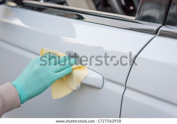 Closeup of hand spraying a blue sanitizer from\
a bottle for disinfecting door handle of a white\
car.Antiseptic,disinfection ,cleanliness and healthcare,Anti\
bacterial and Corona virus,\
COVID-19.v