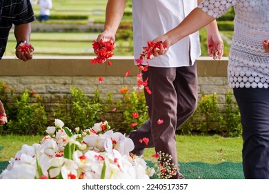 Closeup of hand spreading rose petals on grave or tabur bunga. - Shutterstock ID 2240517357