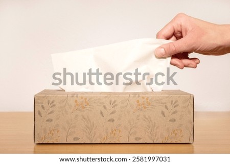Close-up of a hand taking a tissue from a box.