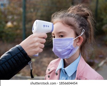 Close-up Of A Hand That Measures Heat With A Non-contact Thermometer. Little Girl With High Temperature Outside