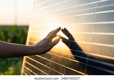 Close-up of a hand touching a solar panel at sunset. - Powered by Shutterstock