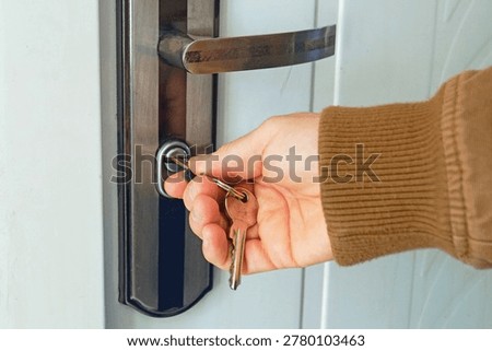 Close-up of hand turning key in front door lock to complete final locking action before leaving residence. Suggests anti-intrusion preparedness, reliable home closure, and disciplined safeguarding of unattended living space.