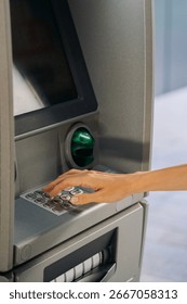 Close-up of a woman’s hand typing a PIN code on the keypad of an ATM cash machine. Concept of banking, finance, money withdrawal, personal security, cashless payments, and modern financial services.