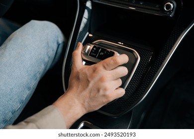 Close-up hand of unrecognizable driver male moving lever arm on gearbox to add speed. Closeup top view of man sitting on driver seat shifting automatic transmission in car