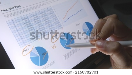 Close-up hand use pen write check growth data number on touch screen laptop note pad app. Loan agent job work at night or MBA tax study in retail graph report  review read saving plan crypto chart.