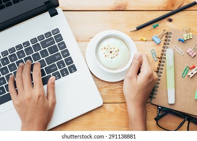 closeup hand using computer and holding coffee on workplace