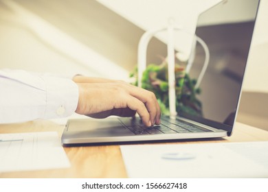 Closeup hand using computer laptop. A young male employee is typing using a computer as a communication technology in a private room, education