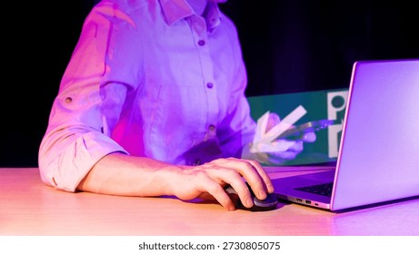 Close-up of hand using computer mouse, laptop displaying holographic arrow pointing to icon in neon purple setting. - Powered by Shutterstock - Get 15% off with code: PIKWIZARD15