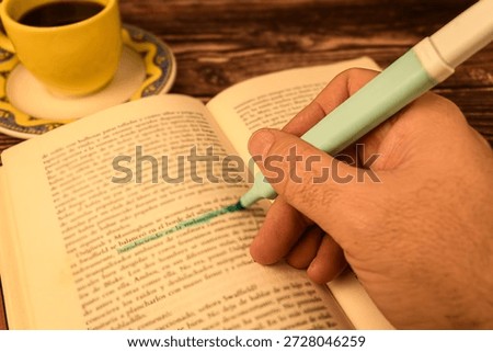 Close-up of a hand using a highlighter on an open book page with warm light. Concept of studying, exam prep, learning and focus.