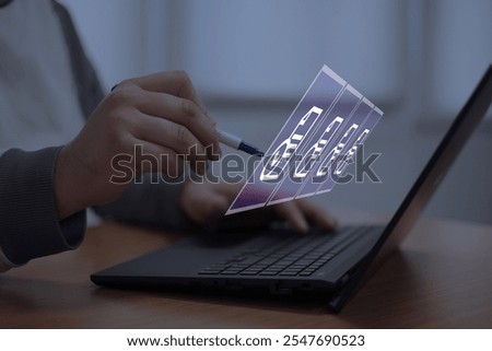 Close-up of a hand using a pen to interact with futuristic digital file icons above a laptop, symbolizing innovative technology, document management, and virtual workspace efficiency.	
