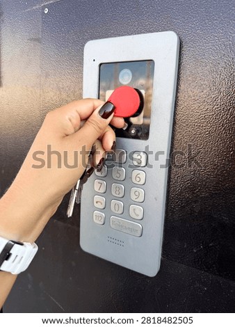 Close-up of a hand using an RFID tag for secure access on a door keypad. Represents modern security and technology.