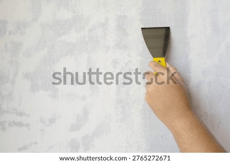 Close-up of Hand Using Scraper Tool to Repair or Smooth Concrete Wall Surface