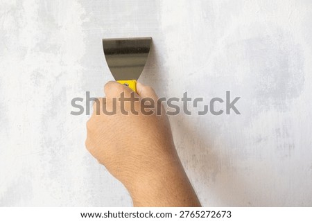 Close-up of Hand Using Scraper Tool to Repair or Smooth Concrete Wall Surface
