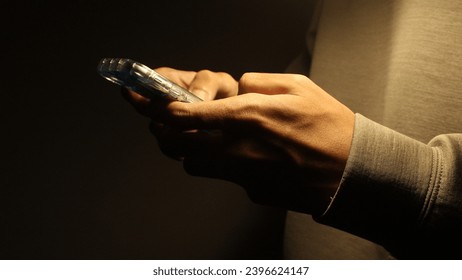 Close-up of Hand Using Smartphone in Dark Room, illustrating a person checking their messages before bed or in a low-light environment