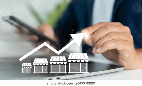 Close-up of a hand using a smartphone with increasing store graph icons, representing franchise business growth, retail expansion, and multi-location store strategy.