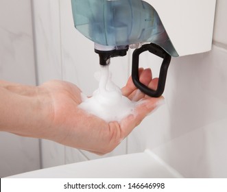 Closeup Of Hand Using Soap Dispenser In Bathroom