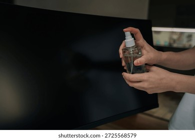 Close-up of hand using soft cloth to carefully clean top and side edge of dark computer monitor, performing routine technology maintenance for clean workspace.