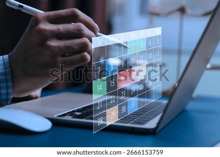 Close-up of hand using stylus with digital calendar interface on laptop, representing online scheduling, time management, productivity planning, event reminder system, and smart business tools.