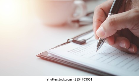 Close-up of Hand using writing pen with questionnaire or paperwork survey question filling in business company personal information form checklist document.