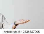 Close-up of a hand in a white shirt gesturing against a plain background. The hand is open, palm up, suggesting offering or presenting. Minimalist and neutral tone.