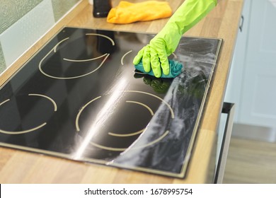 Closeup of hand woman cleaning modern cooking glass ceramic electric surface with sponge and detergent