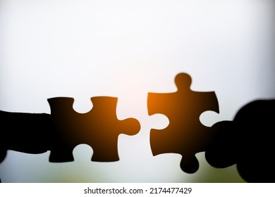 Closeup Hand Of Woman Connecting Jigsaw Puzzle With Sunlight Effect, Business Solutions, Success And Strategy Concept