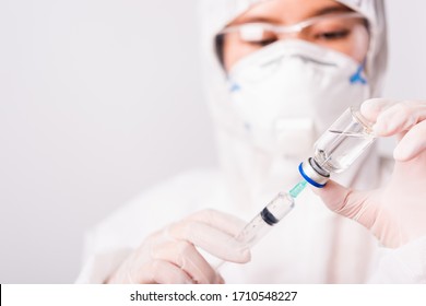 Nahaufnahme der Hand von Ärztin oder Wissenschaftlerin in der PSA-Suite Uniform mit Gesichtsmaske Schutzmittel im Labor halten Arzneimittel Flasche und Spritze mit Flasche mit Flasche und Spritze, Coronavirus oder COVID-19 Konzept weiß einzeln