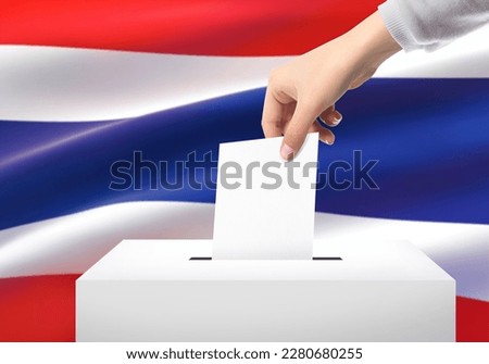 Close-up hand of woman hand woman holding ballot paper for election vote at thailand national flag background. Thailand voting concept.