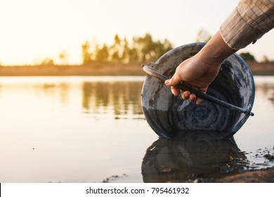 Close-up hand of woman holding a bucket on lake, crisis of water and drought