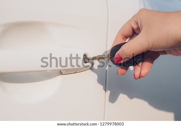 Closeup hand\
woman holding key opening car\
door.
