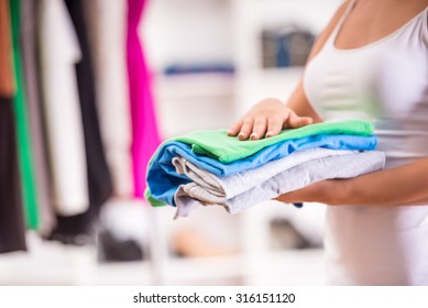 Close-up Hand Of Woman Holding A Pile Of Clothes.