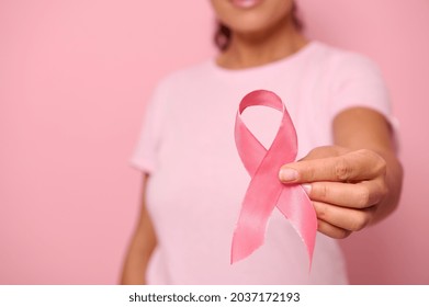 Close-up. Hand of woman in pink t-shirt, holding pink ribbon. World Cancer Day. Breast and abdominal cancer awareness, October Pink day on colored background, copy space. Breast cancer support concept - Shutterstock ID 2037172193