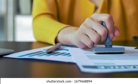 Close-up Hand Woman Stamping  With Approved Stamp On Document At Desk